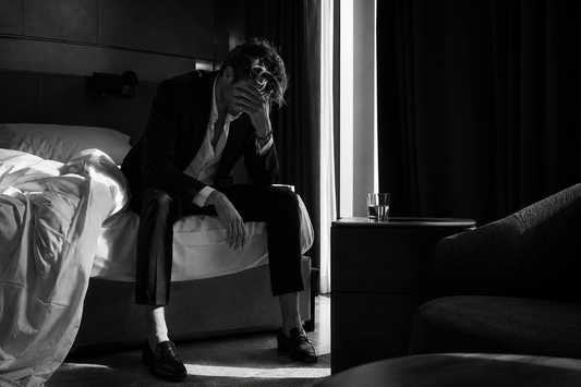 Hungover person sitting on a bed in morning light after a night out