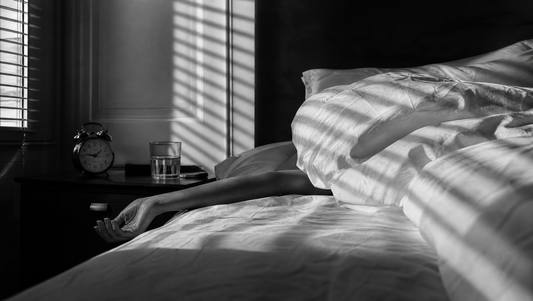 Morning sun through blinds on a rumpled bed with an alarm clock - how long a hangover actually lasts